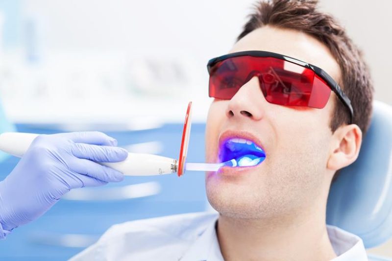 Man undergoing dental curing light treatment wearing protective glasses