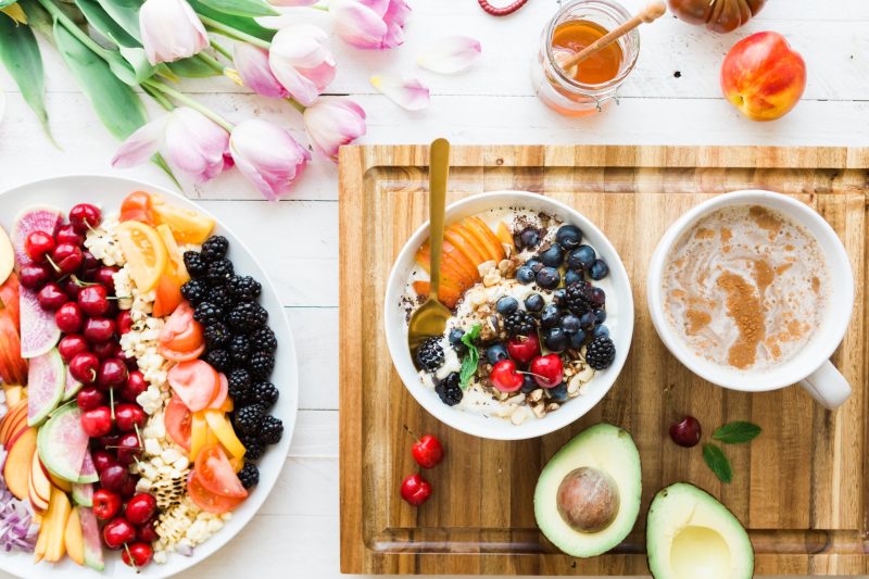 Healthy breakfast with fresh fruits, yogurt, avocado, and coffee.