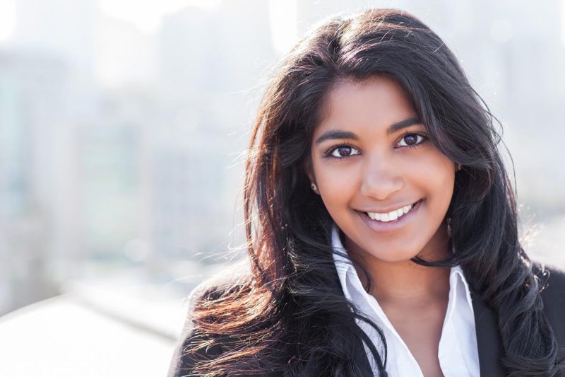 Smiling professional woman with long black hair in office background